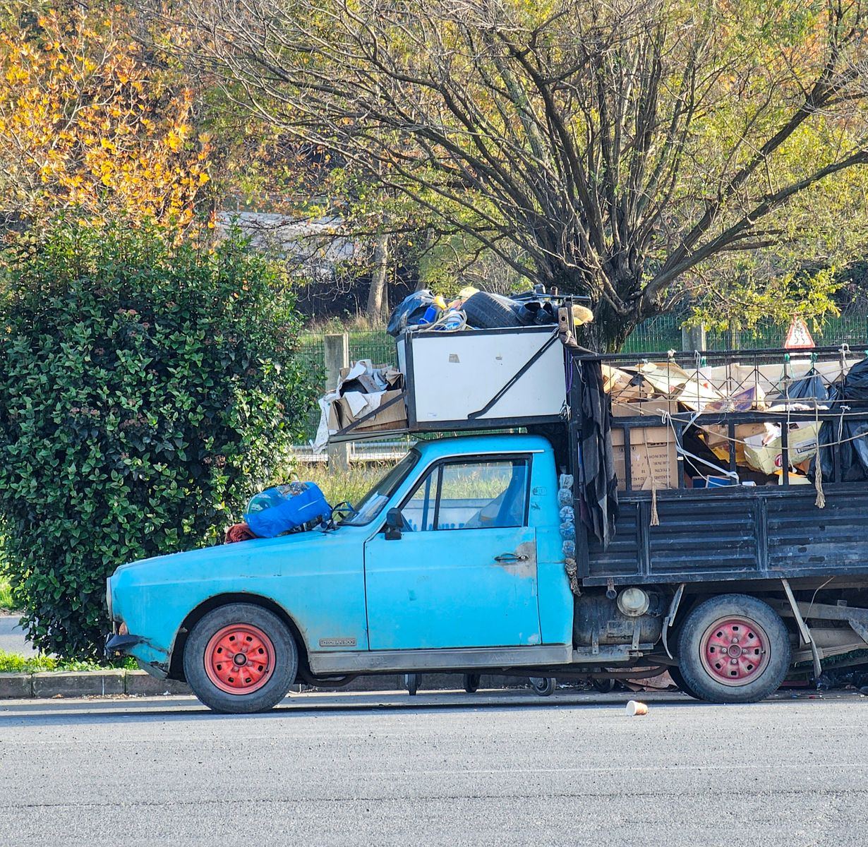 A pickup truck loaded high with old furniture, boxes and junk, ready to haul to the dump